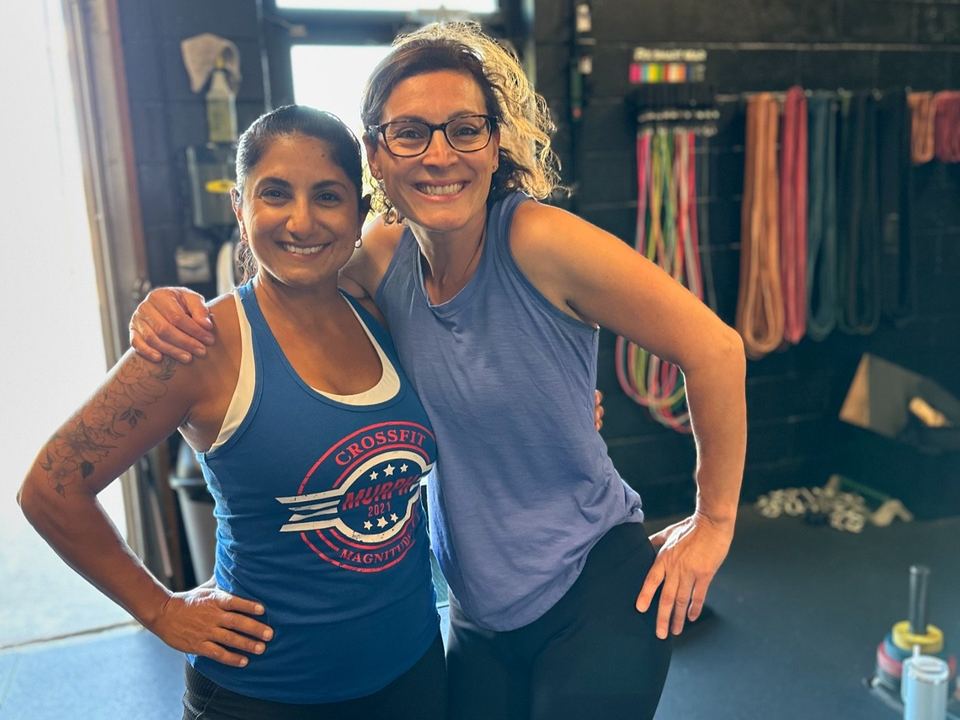 Two smiling CrossFit Magnitude members, arm in arm after a workout