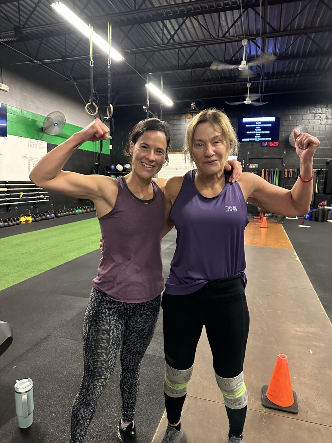 Two CrossFit Magnitude members flexing and smiling after class